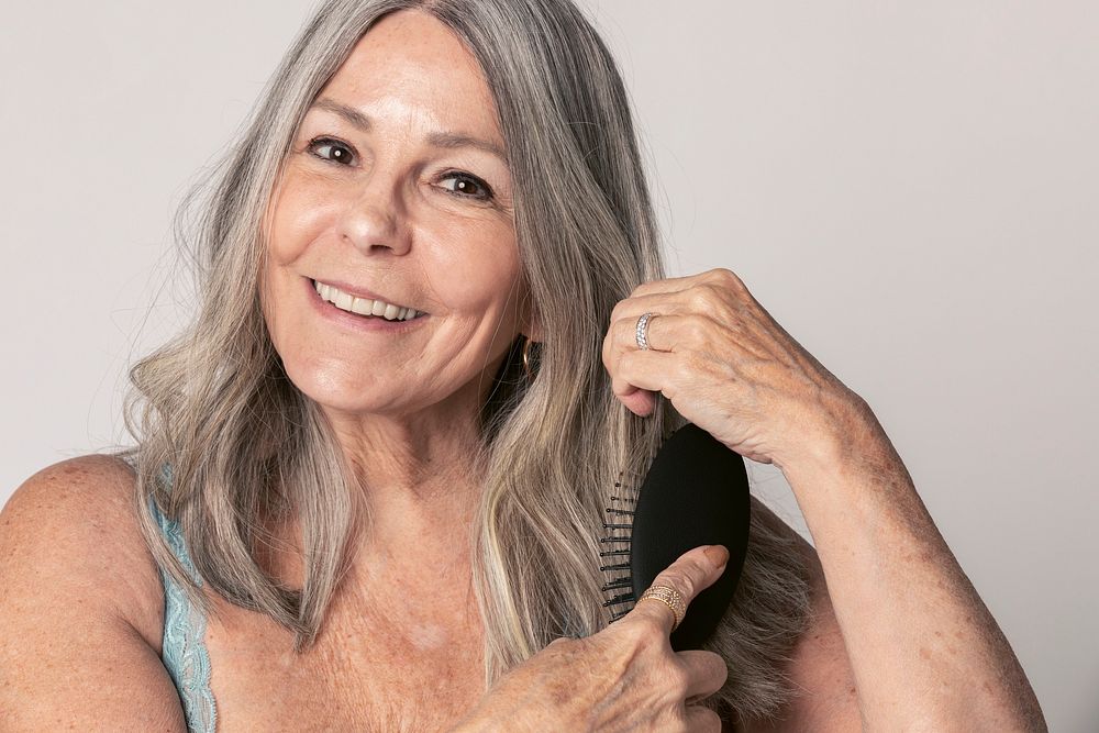 Cheeful senior woman brushing her hair