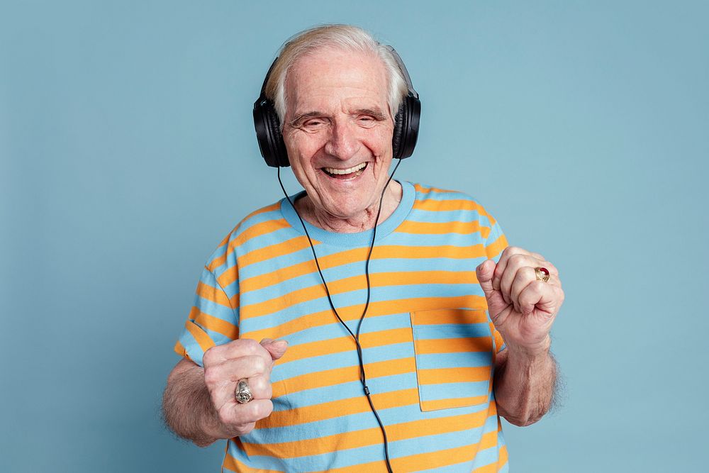 Happy senior man dancing while listening to music with headphones