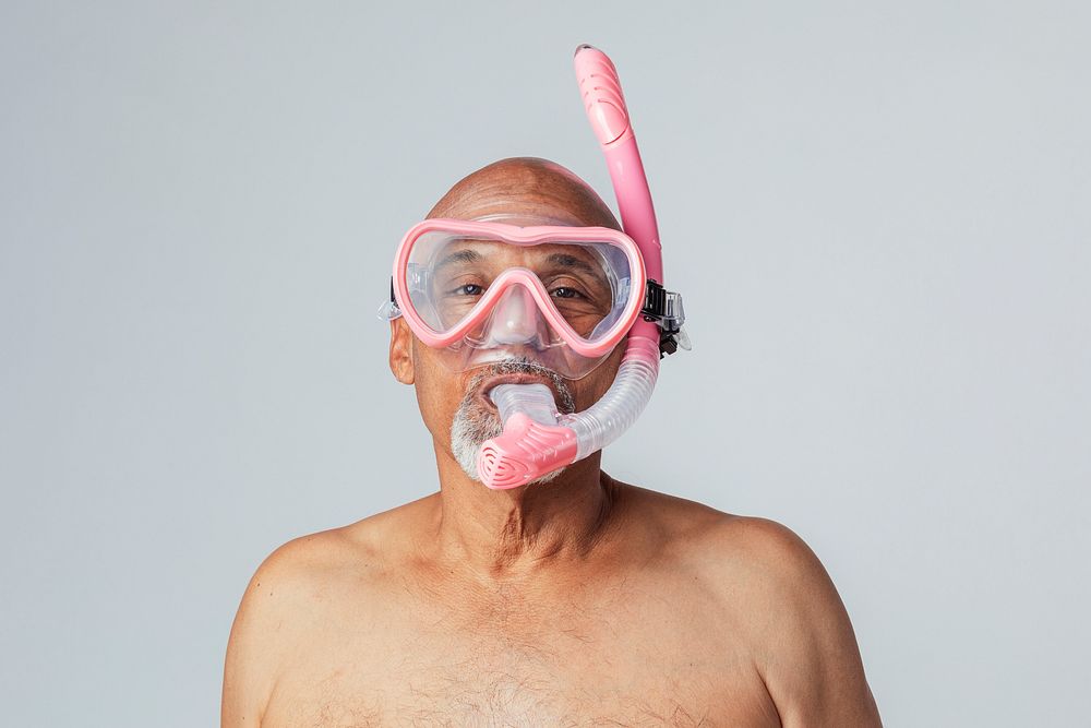 Funny senior African American man wearing a pink snorkel and goggles