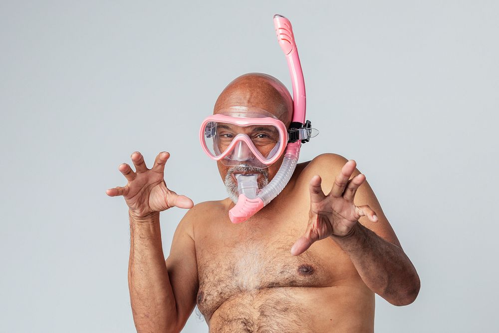 Funny senior African American man wearing a pink snorkel and goggles