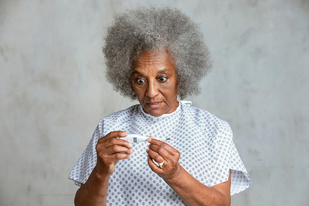 Shocked senior patient checking her temperature