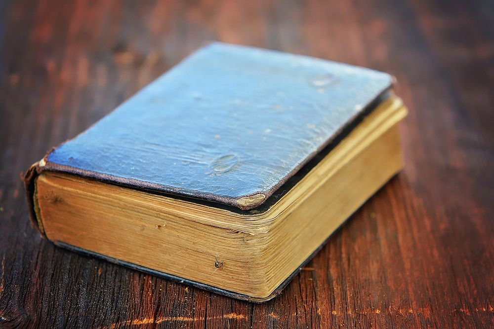 Free old closed book on wooden table photo, public domain CC0 image.