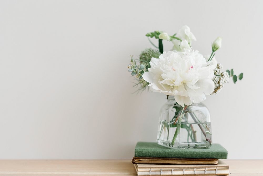 White flower bouquet in a cleared vase on a stack of books