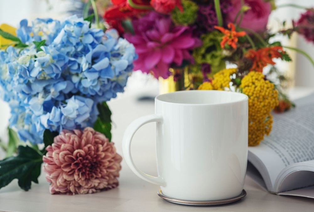 White coffee cup among flowers on a table