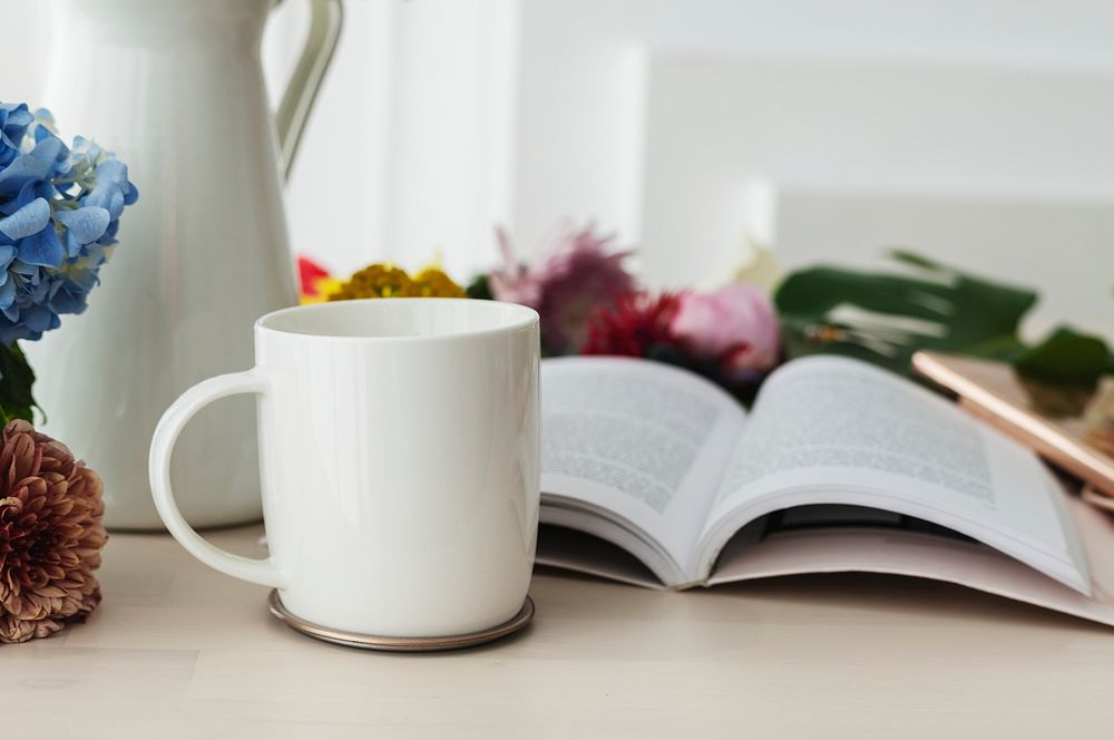 White coffee cup mockup by a book