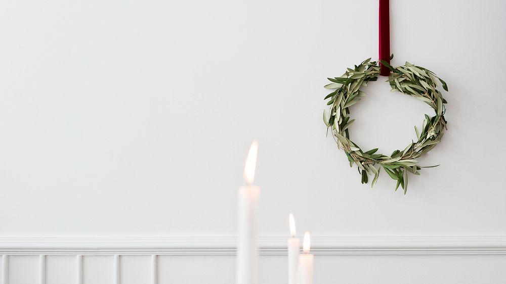 Christmas wreath on a white wall with lighted white pillar candles