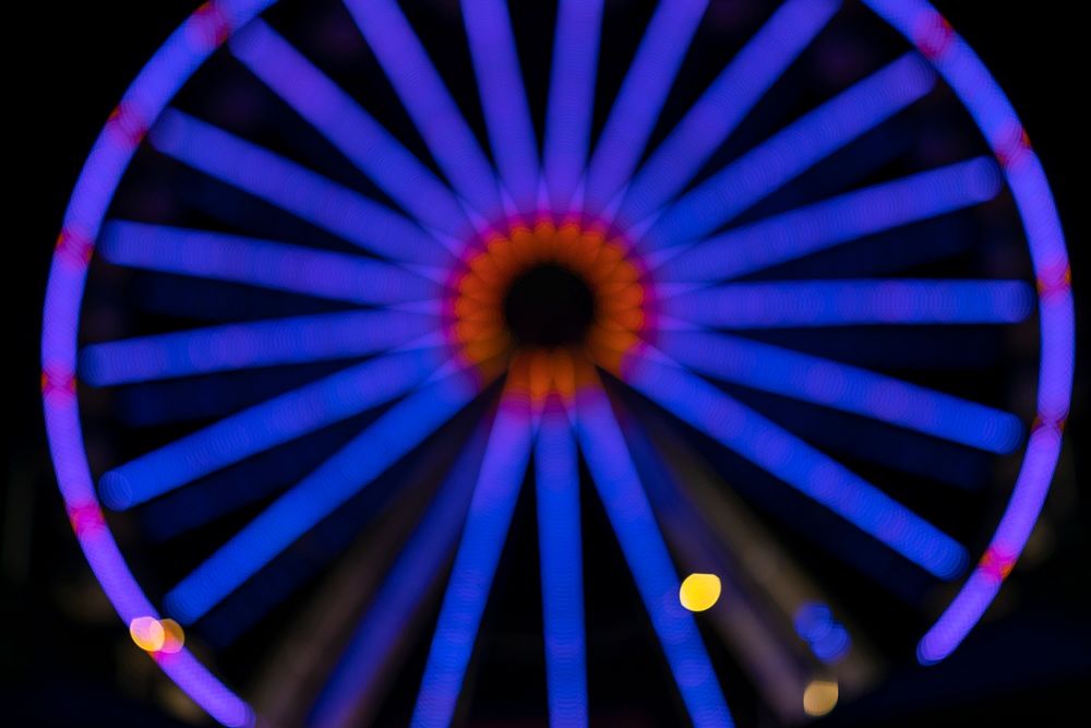 Blurry blue neon Ferris wheel in a carnival at night