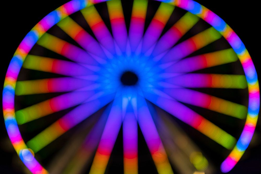 Blurry colorful neon Ferris wheel in a carnival at night