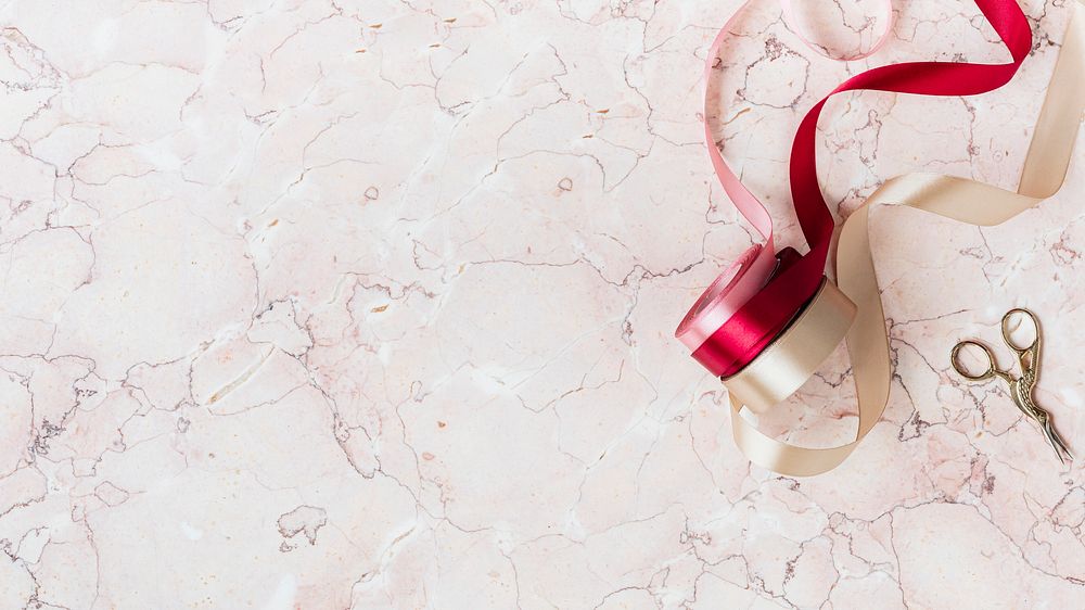 Rolls of ribbon on a pink marble background