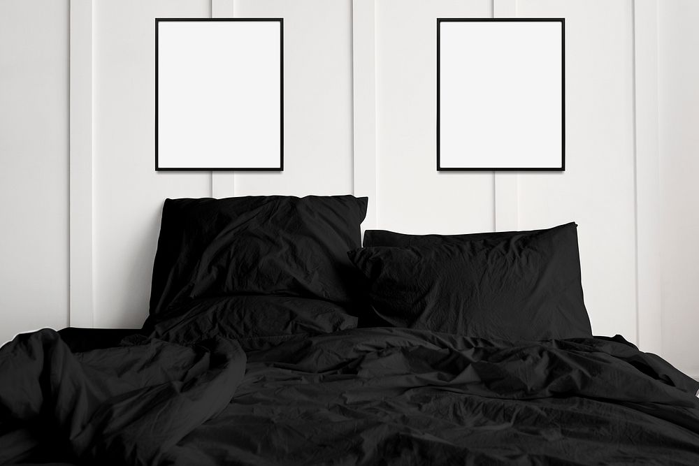 Blank picture frames hanging above a black bed