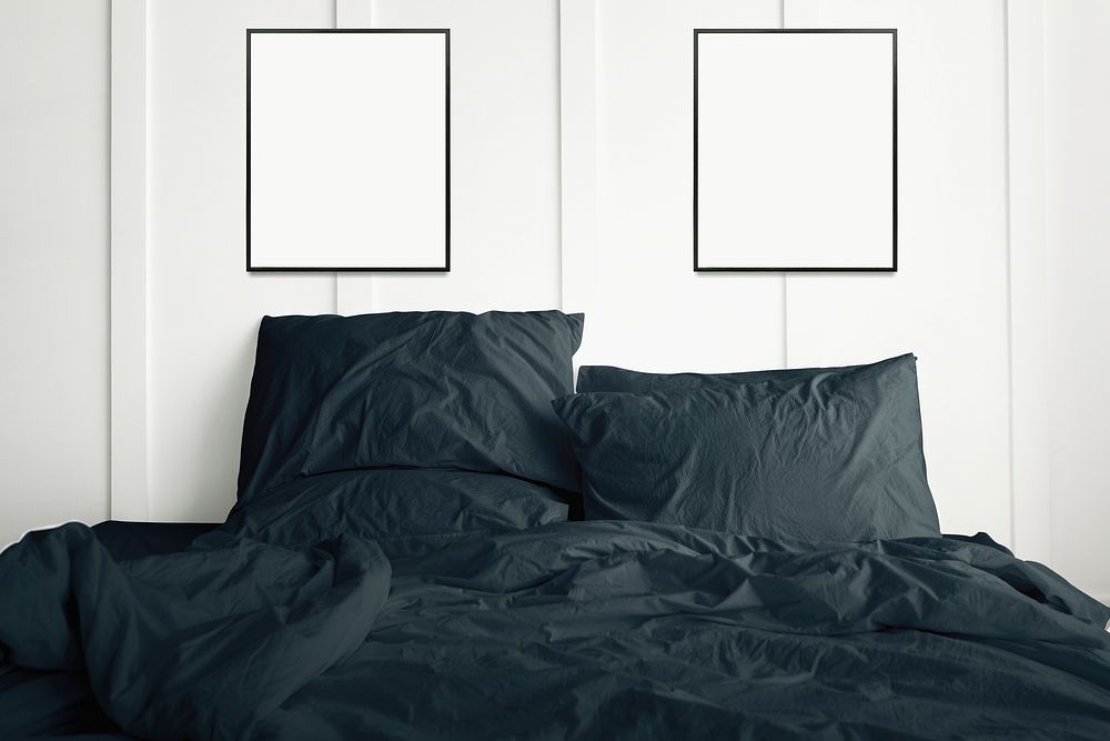 Blank picture frames hanging above a dark green bed