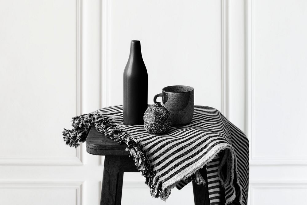 Black ceramic vase with a mug on a wooden stool 