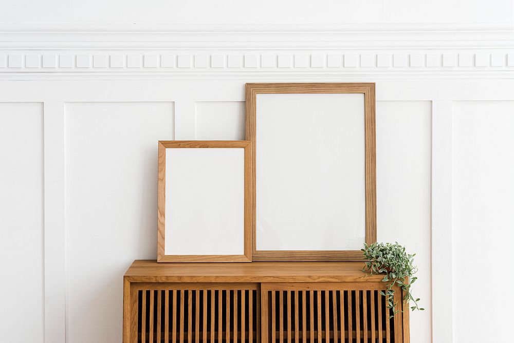 Two picture frames on a wooden sideboard