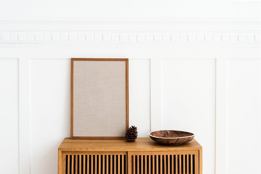 Blank large frame on a wooden sideboard in a living room
