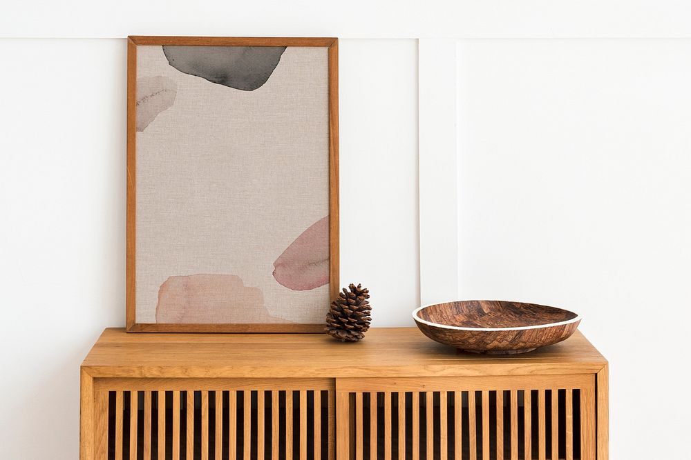 Picture frame mockup on a wooden sideboard table with a pine cone and a wooden bowl 