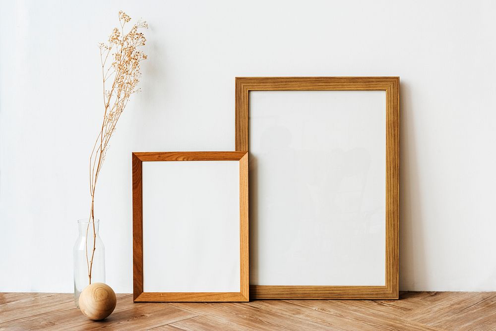 Picture frames on a wooden sideboard table with dried flowers 