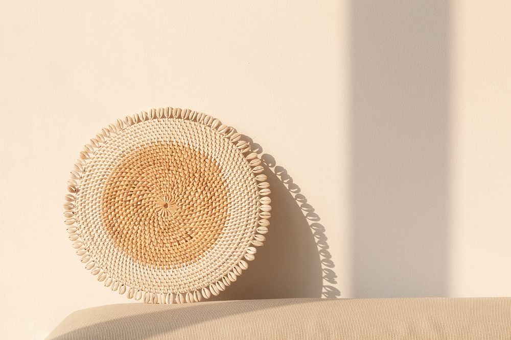 Round rattan paper plate holder by a beige wall