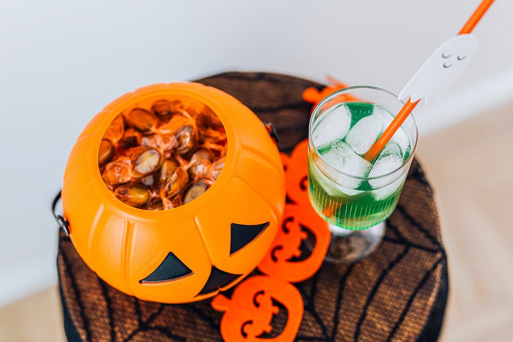 Halloween drink and a pumpkin basket filled with sugar candies on a table