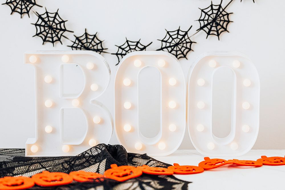 Lighted boo sign on a white table with Halloween decoration 