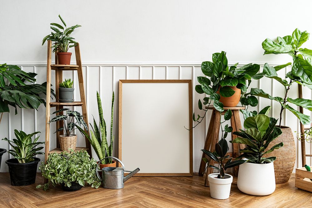 Blank picture frame by a houseplant corner on a parquet floor
