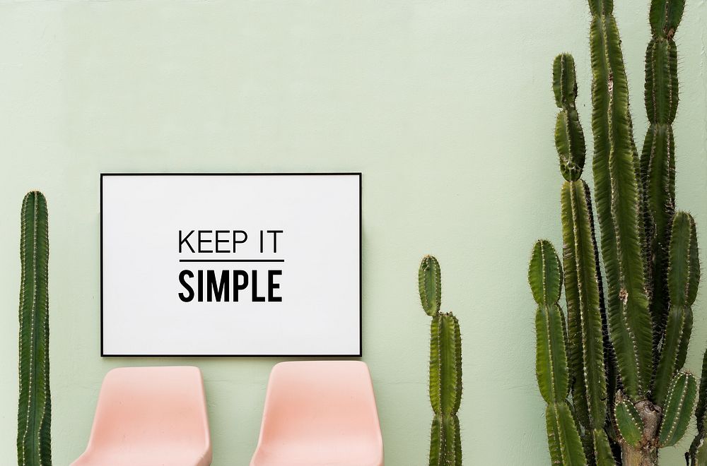 Keep it simple in white frame hanging on green wall