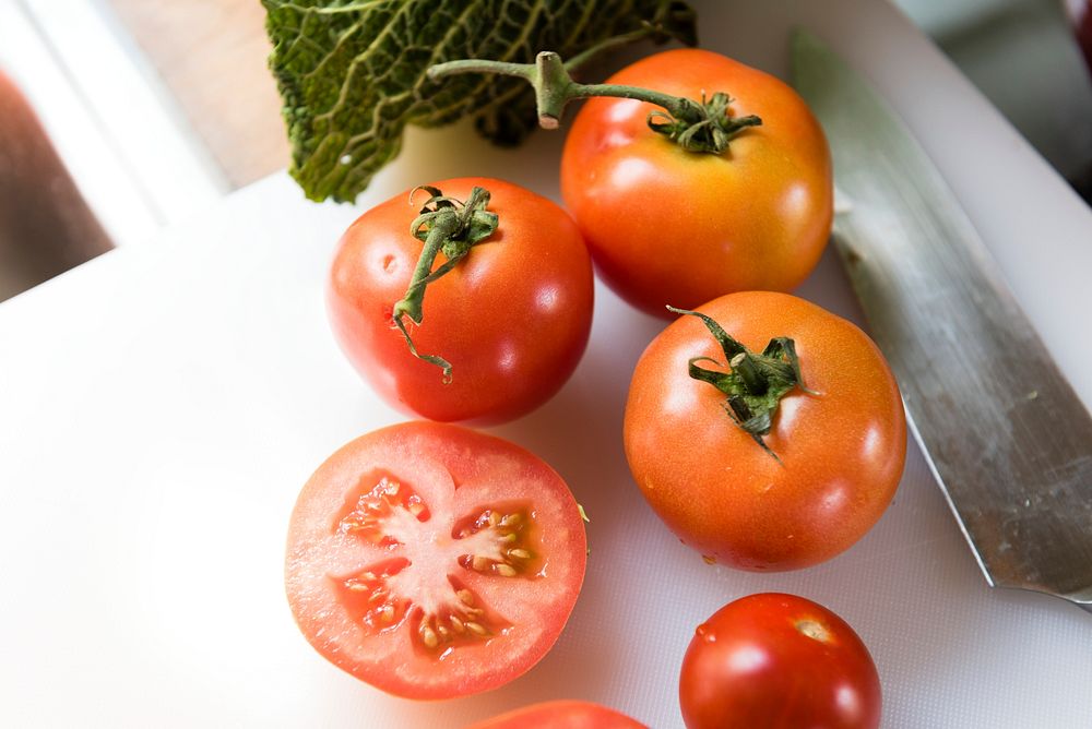 Fresh tomatoes on a plastic cutting board