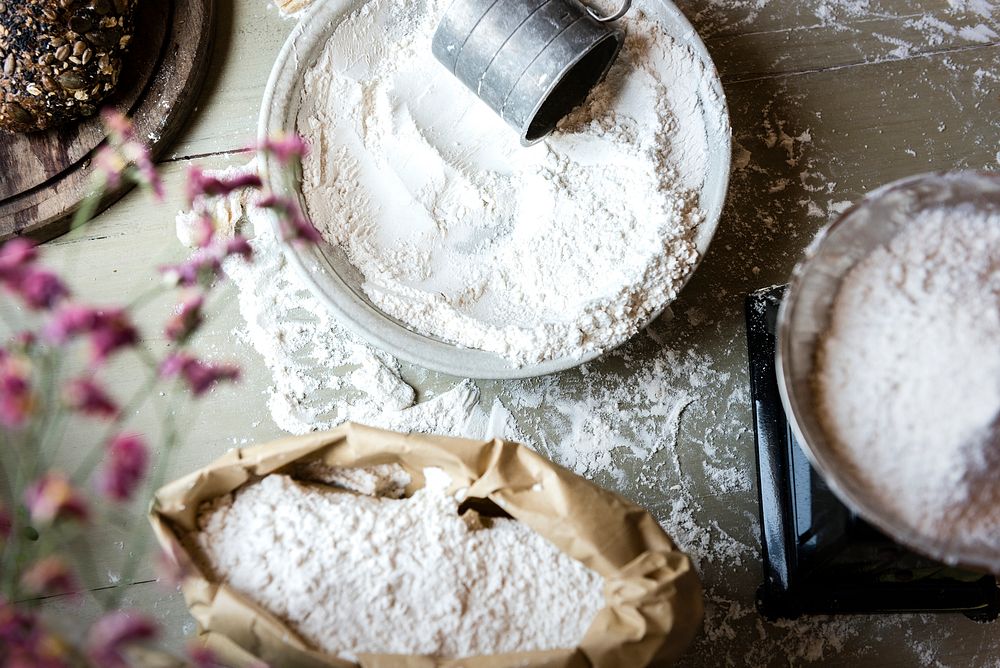 Paper bag and bowls of flour on a wooden table