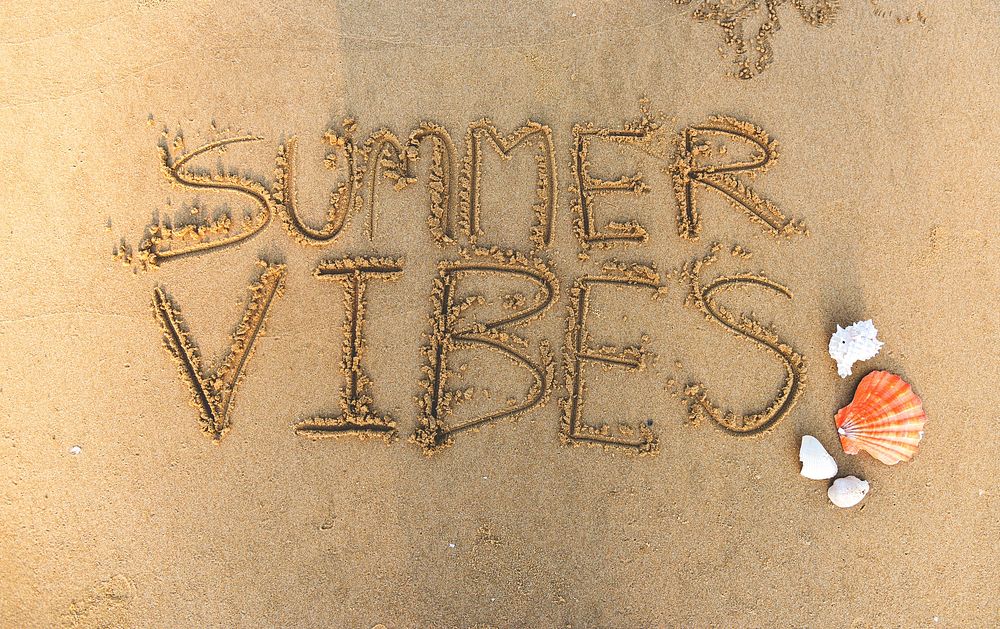 Summer vibes written in the sand