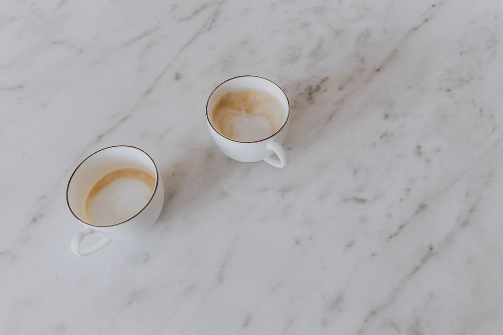 Two cups of latte on a marble table