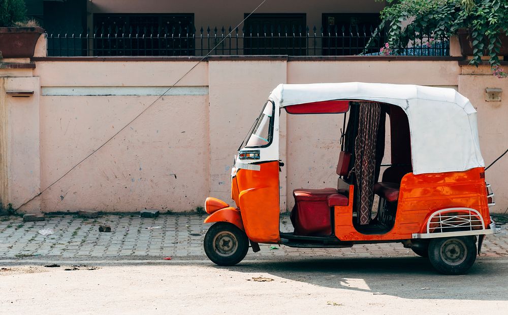Traditional Indian white and orange tricycle parking on a street in Varanasi, India