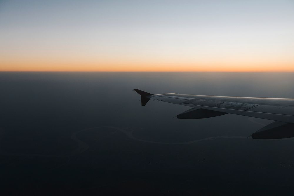 Wing of a plane flying in a dusky sky