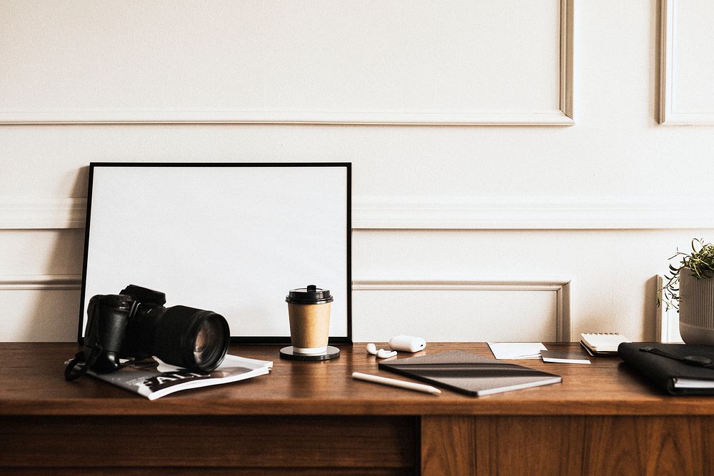 Blank frame with an analog camera on a wooden table