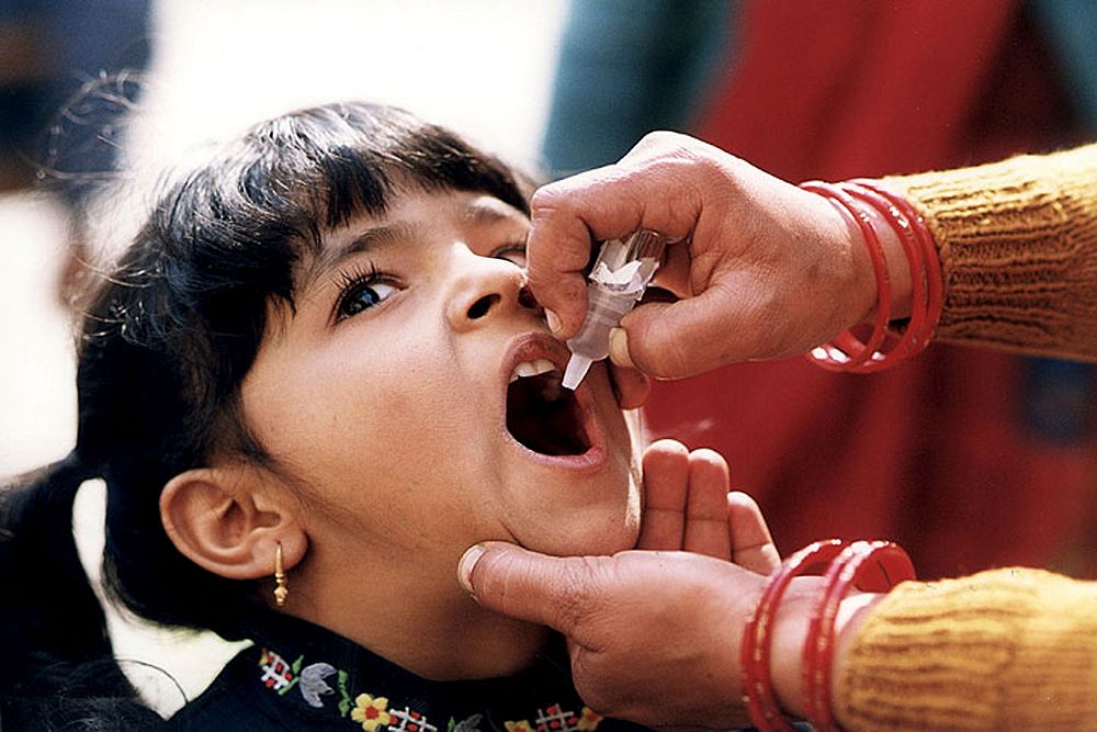 A young Indian girl receiving a dose of oral polio vaccine by a trained healthcare worker. Original image sourced from US…