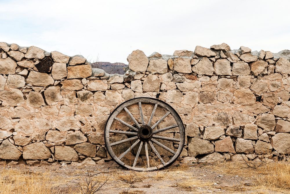 Wagon wheel against a stone fence at Hueco Tanks State Park, northwest of El Paso, USA. Original image from Carol M.…