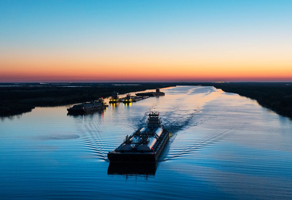 Dusk shot of barges traversing a short canal that connects the Sabine Pass waterway separating Texas from Louisians, and the…