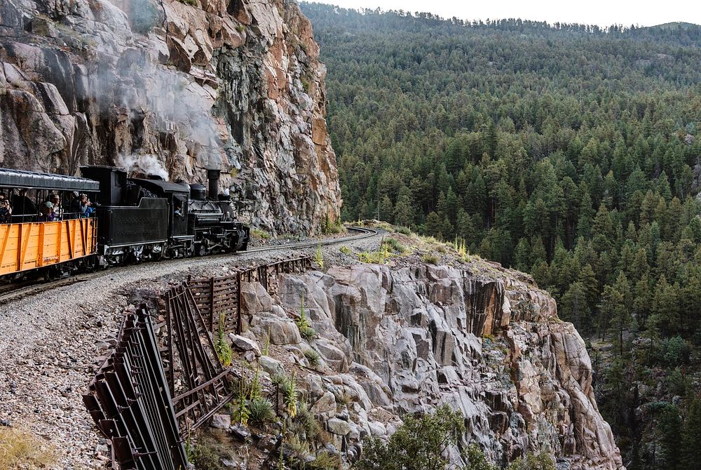 A Durango & Silverton Narrow-Guage Scenic Railroad train, pulled by a vintage steam locomotive, navigates a San Juan…