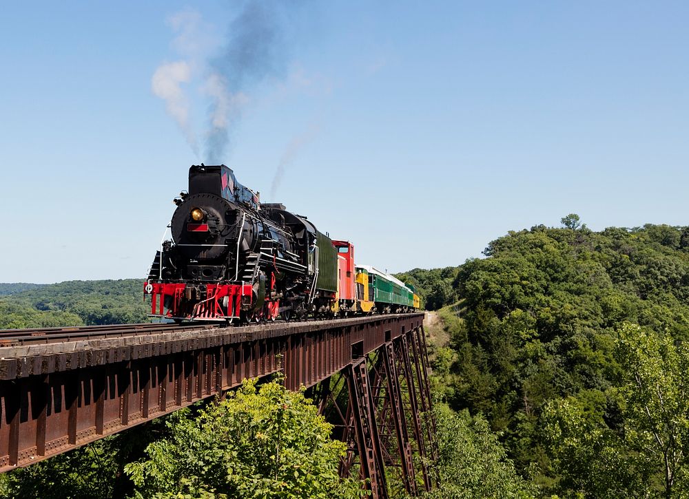 A steam train on a heritage railroad that operates excursions in Boone County, Iowa, crosses the 156-foot-tall Bass Point…