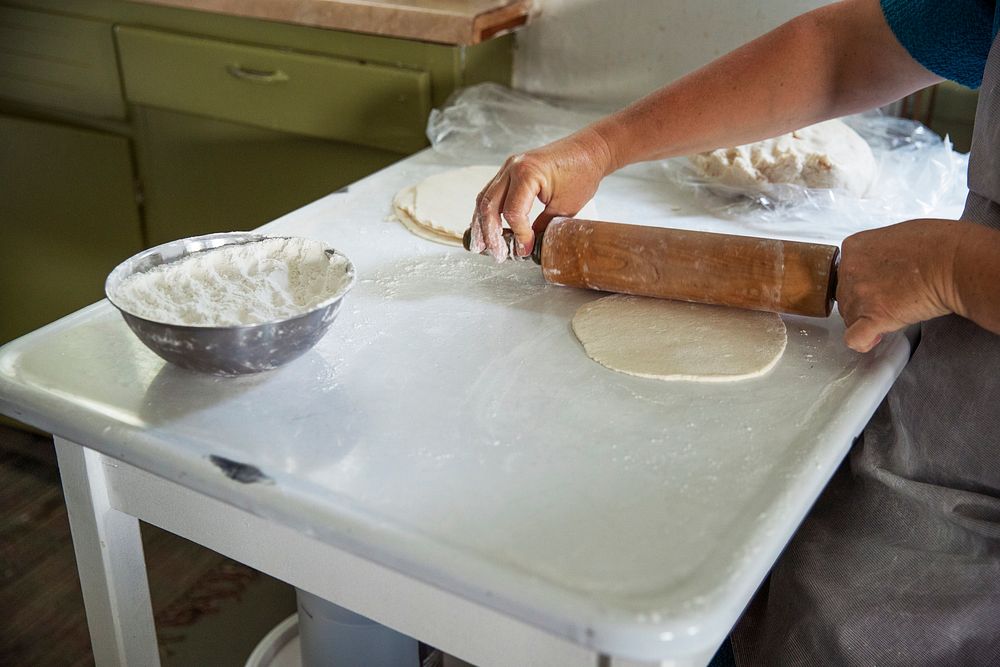 An Amish woman rolls dough to make small fried pies inside the farmhouse at Yoder's Amish Home. Original image from Carol M.…