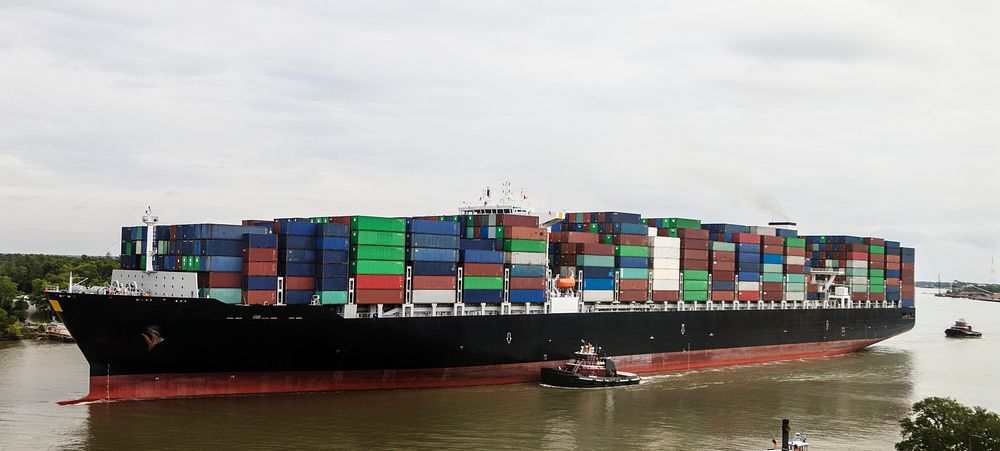 With a tugboat's help, an exceptionally heavy-laden oceangoing container ship plies the busy Savannah River in Savannah…