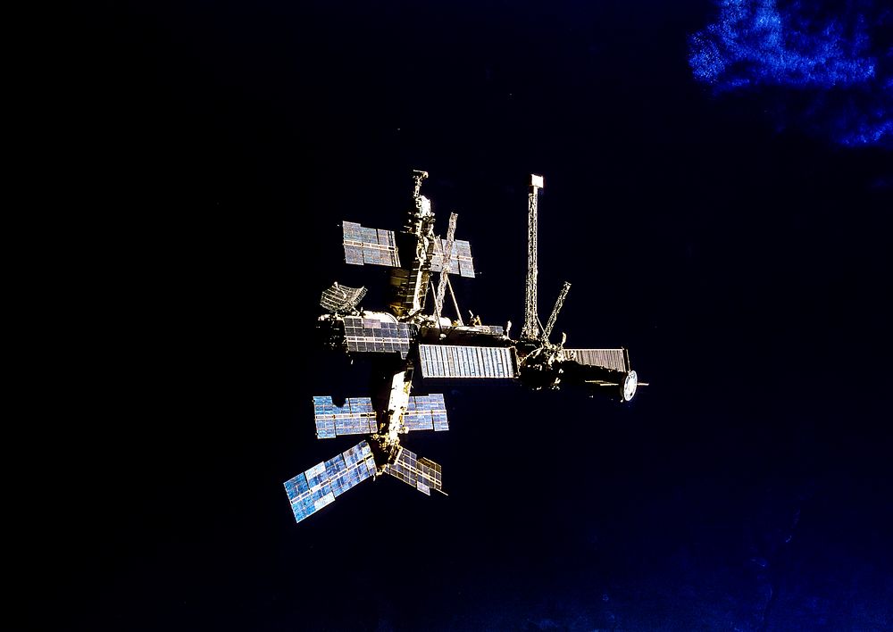 Following undocking from the Space Shuttle Atlantis, Russia's Mir Space Station is backdropped against dark blue water on…