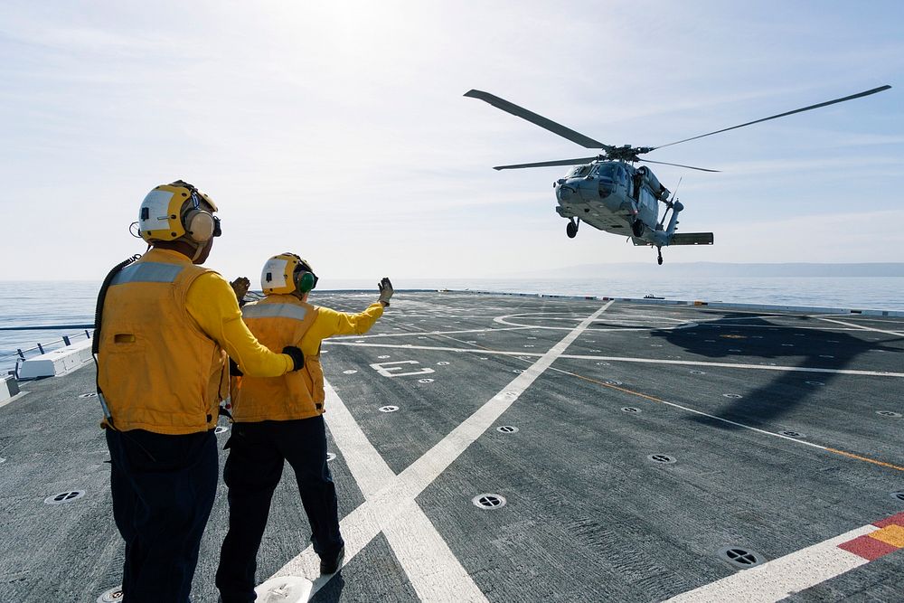 On the top deck of the USS San Diego, U.S. Navy personnel monitor a helicopter landing after an Orion underway recovery…