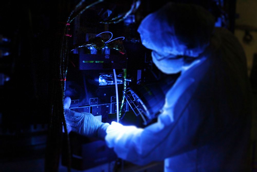 Using a black light, a technician closely inspects one of NASA's twin Radiation Belt Storm Probes inside the clean room high…