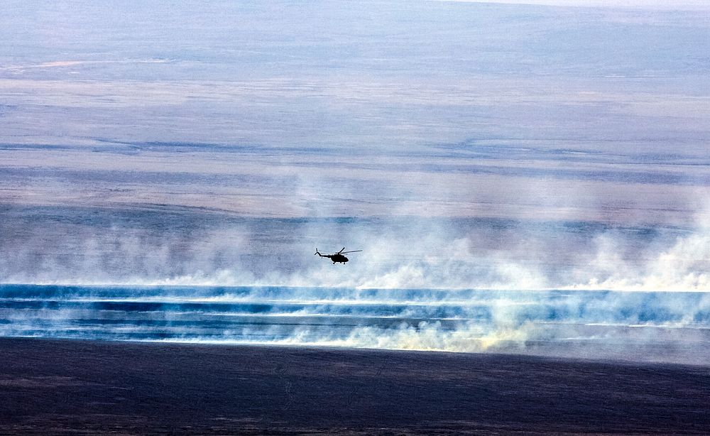 A Russian search and rescue helicopter flies over the burning Kazakh steppe. Original from NASA. Digitally enhanced by…