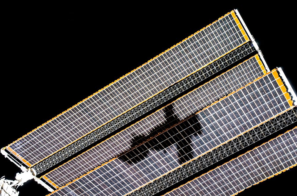 The shadow of the Soyuz TMA-14 spacecraft is visible against solar array panels of the International Space Station during…