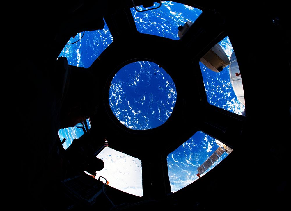 A blue and white part of Earth is visible through the windows in the Cupola of the International Space Station, 22 August…