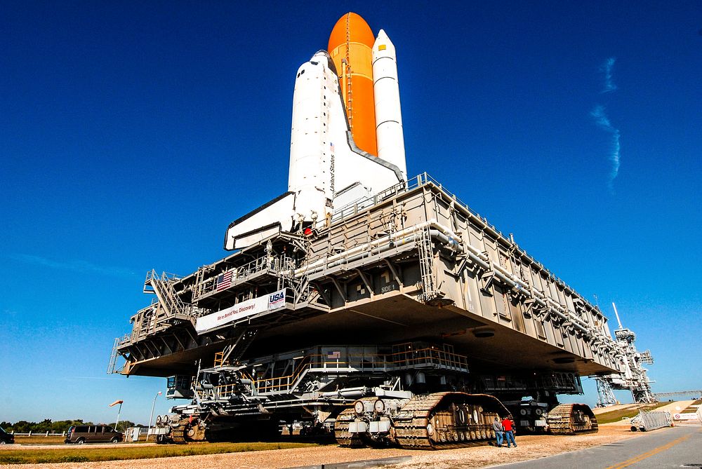 Space shuttle Discovery, atop the mobile launcher platform and crawler-transporter, approaches the ramp to Launch Pad 39A at…