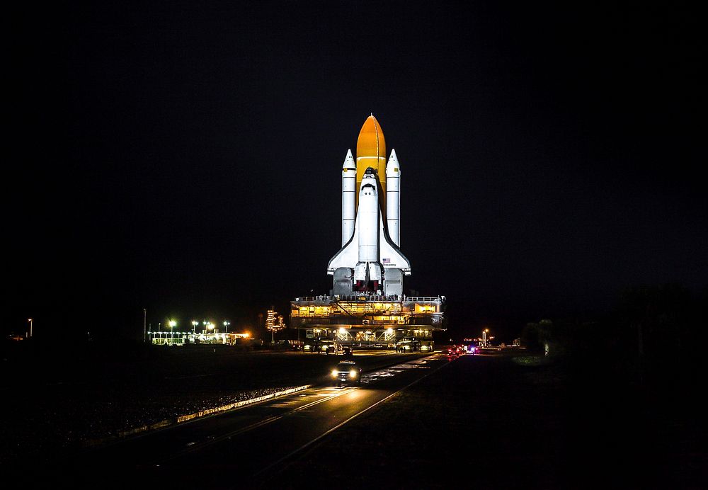 Xenon lights illuminate space shuttle Discovery as it makes its nighttime trek, known as rollout, from the Vehicle Assembly…