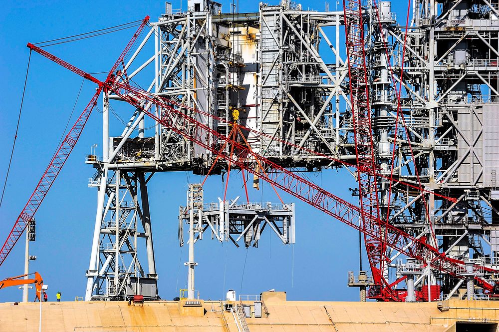 A large crane dismantles another level of the fixed service structure on Launch Pad 39B at NASA's Kennedy Space Center in…