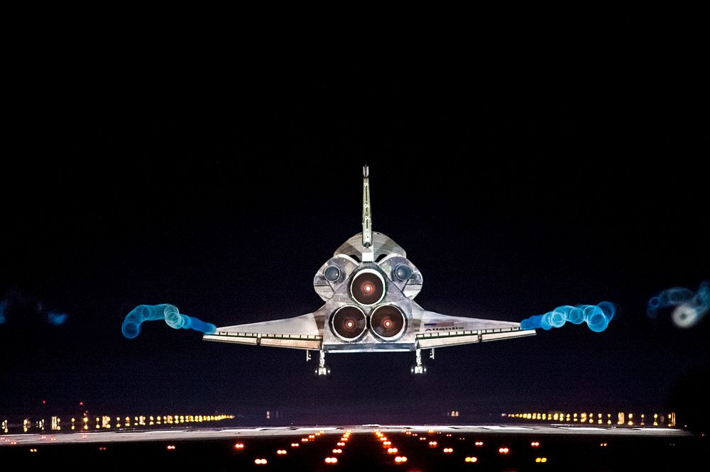 Vapor trails follow space shuttle Atlantis as it approaches Runway 15 on the Shuttle Landing Facility at NASA's Kennedy…