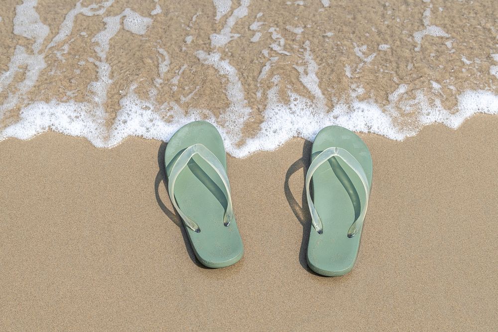Green slippers on the beach background
